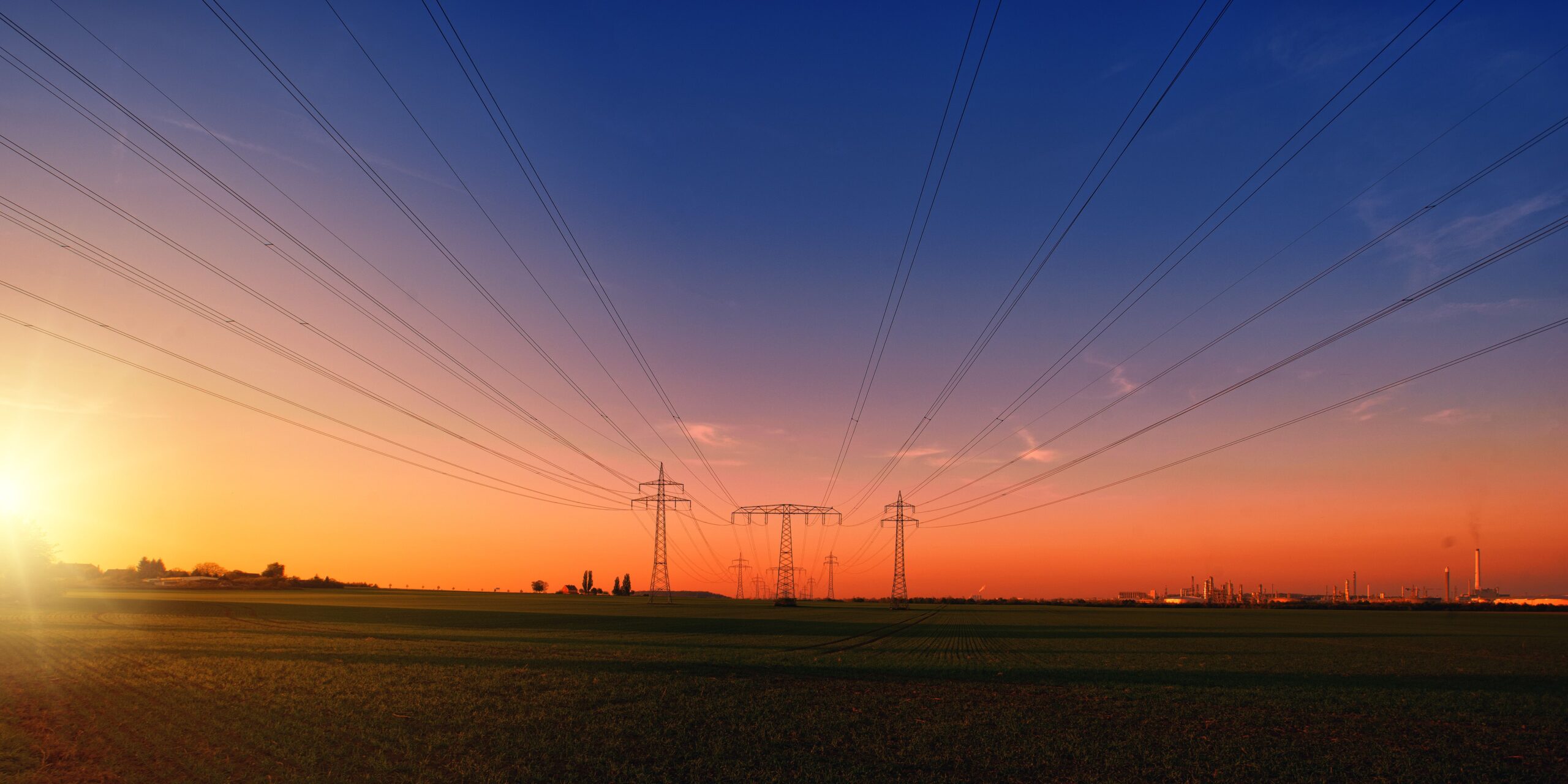 Power lines stretch across a rural landscape at dusk, capturing the serene beauty of the energy infrastructure.